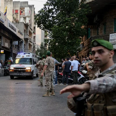 Lebanese army soldiers stand near an ambulance driving through the street.