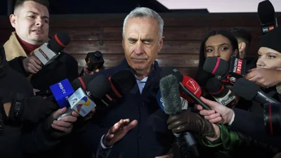 Calin Georgescu, running as an independent candidate for president touches his face while speaking to media, in Izvorani, 26 November 2024