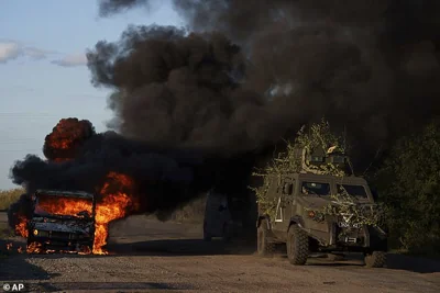 A Ukrainian armoured military vehicle travels past a burned car near the Russian-Ukrainian border, Sumy region, Ukraine, Wednesday, Aug. 14, 2024