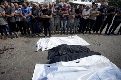 Palestinians pray next to the bodies of their relatives killed in the Israeli bombardment of the Gaza Strip, at a hospital in Deir al-Balah, Sunday, July 21, 2024.