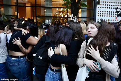 Mourning fans of Liam Payne embrace after Geoff Payne, father of Liam, visited the memorial