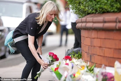 A woman leaves flowers near the scene in Southport this morning after yesterday's incident