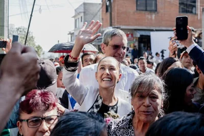 Claudia Sheinbaum waves to people from a crowd. 