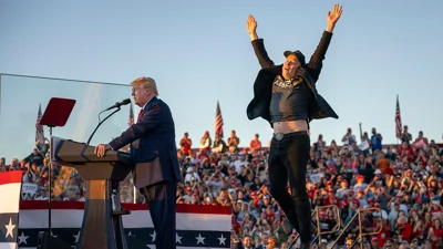 Tesla CEO Elon Musk jumping on stage behind Donald Trump 