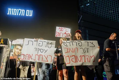 Demonstrators in Tel Aviv last night hold signs demanding a ceasefire and a hostage deal