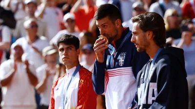 Gold medallist Novak Djokovic of Serbia kisses his medal on the podium next to silver medallist Carlos Alcaraz of Spain and bronze medallist Lorenzo Musetti of Italy(REUTERS)