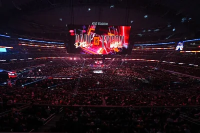 A large screen suspended over a packed stadium crowd says “Paul vs Tyson.”