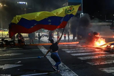 A protester runs waving a Venezuelan flag during a protest against the official results of the presidential election on July 29, 2024 in Caracas