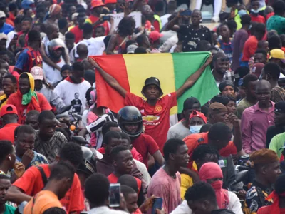 File. A man holds up a Guinean national in Conakry on 18 September 2021