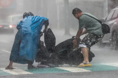 A man (right) helps a motorist with a scooter amid heavy rain due to Super Typhoon Kong-rey in Keelung on October 31, 2024. AFP PHOTO