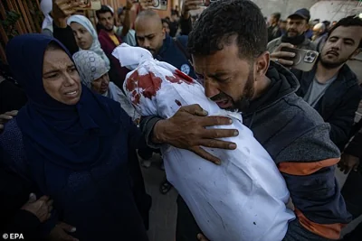 A father mourns as he carries the body of his son, who was killed in an Israeli airstrike, at Nasser Hospital in Khan Yunis, southern Gaza Strip, 23 November 2024