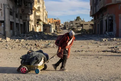 NOWHERE TO GO A displaced Palestinian woman carries her belongings as she flees Beit Lahia in the northern Gaza Strip walking on the main Salah al-Din road on Nov. 17, 2024