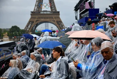 Torrential rain in Paris has marred the opening ceremony with many spectators seen wearing ponchos and holding umbrellas