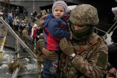 Український військовий тримає дитину, допомагаючи цивільним евакуюватися з-під зруйнованого мосту в Ірпені, 5 березня 2022 року