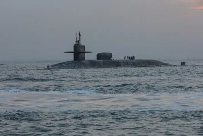 A submarine is partially visible in coastal waters.