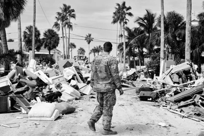 A man walking among debris on a street ravaged by Hurricane Helene.