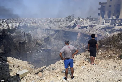 People check a damaged building at the site of an Israeli airstrike in Choueifat, south east of Beirut