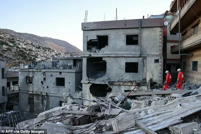 Rescuers check the destruction following an overnight Israeli airstrike on Friday