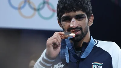 Bronze medallist Aman Sehrawat of India bites his medal.(REUTERS)