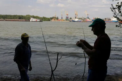 Two Romanian fishermen on the banks of the River Danube. The Ukrainian port of Izmail is on the other bank behind them.