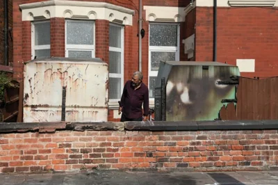 A man inspects damaged clothing bins and a fence of the Southport Islamic Society Mosque, after a violent protest, following a vigil for victims of the knife attack in Southport, Britain July 31, 2024. REUTERS/Temilade Adelaja