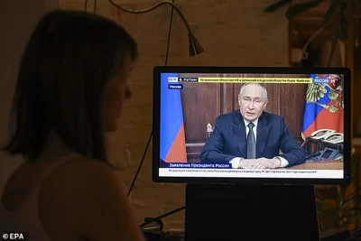 A person watches a televised address by the Russian President in Moscow