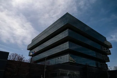 An exterior view of the headquarters of Purdue Pharma, a massive cantilevered building with glass walls.