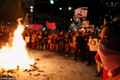 Demonstrators gather around a fire during a demonstration against Israeli Prime Minister Benjamin Netanyahu's government on Saturday night