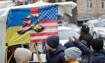 Ukrainians pass a souvenir stall with a flag depicting Ukrainian and US flags, in downtown Kyiv, Ukraine