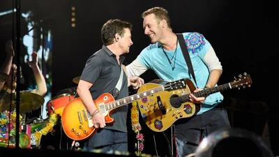 Michael J. Fox and Chris Martin on stage with guitars