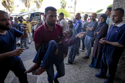 Palestinian man carries an injured child