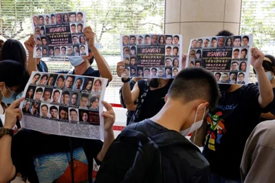 Supporters hold up placards among people queuing up at the West Kowloon Magistrates' Courts for a hearing of 47 pro-democracy activists in Hong Kong on July 8, 2021. REUTERS/Tyrone Siu