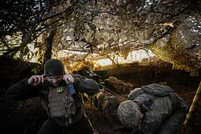 A Ukrainian soldier covers his ears as he turns away from a blast. 