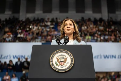 Kamala Harris stands at a lectern bearing the seal of the Vice President of the United States during an indoor campaign rally. 