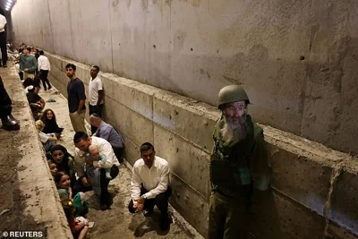 People take shelter during an air raid siren, amid cross-border hostilities between Hezbollah and Israel