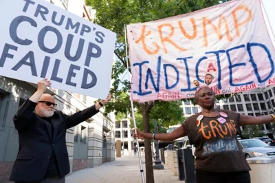 Protesters in Washington, DC, hold up signs that read "Trump's coup failed" and "Trump indicted."