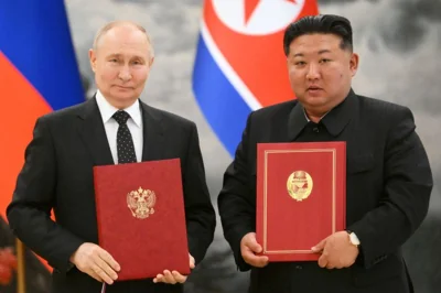 Russia's President Vladimir Putin and North Korea's leader Kim Jong Un pose with their signed bilateral agreement