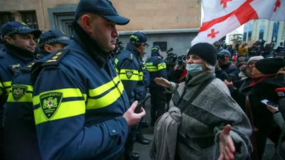 Жінка жестом стоїть перед поліцією, яка блокує вхід до будівлі парламенту, під час мітингу з вимогою нових парламентських виборів у країні, Тбілісі, Грузія, 25 листопада 2024 року