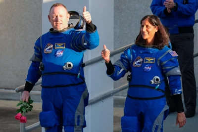 Butch Wilmore, left, and Suni Williams in their space suits give thumbs up