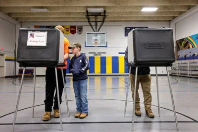 A boy watches his father cast a ballot in the US election