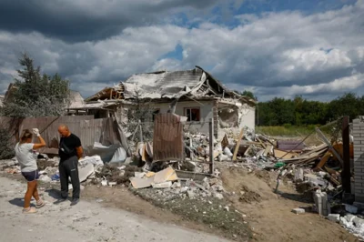 Local residents stand next to a residential building heavily damaged during a Russian missile strike, amid Russia's attack on Ukraine, in the village of Rozhivka in Kyiv region, Ukraine August 11, 2024. REUTERS/Valentyn Ogirenko TPX IMAGES OF THE DAY