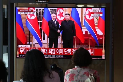 People watch a screen showing Kim Jong-un, right, and Vladimir V. Putin in a news broadcast.