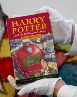 An art handler at Sotheby's New Yorks holds up the first Harry Potter book