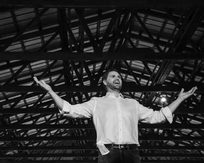 A black-and-white photo of JD Vance with his arms outstretched.