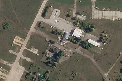 A satellite image showed a damaged hangar at an airfield that was largely surrounded grassy areas. 